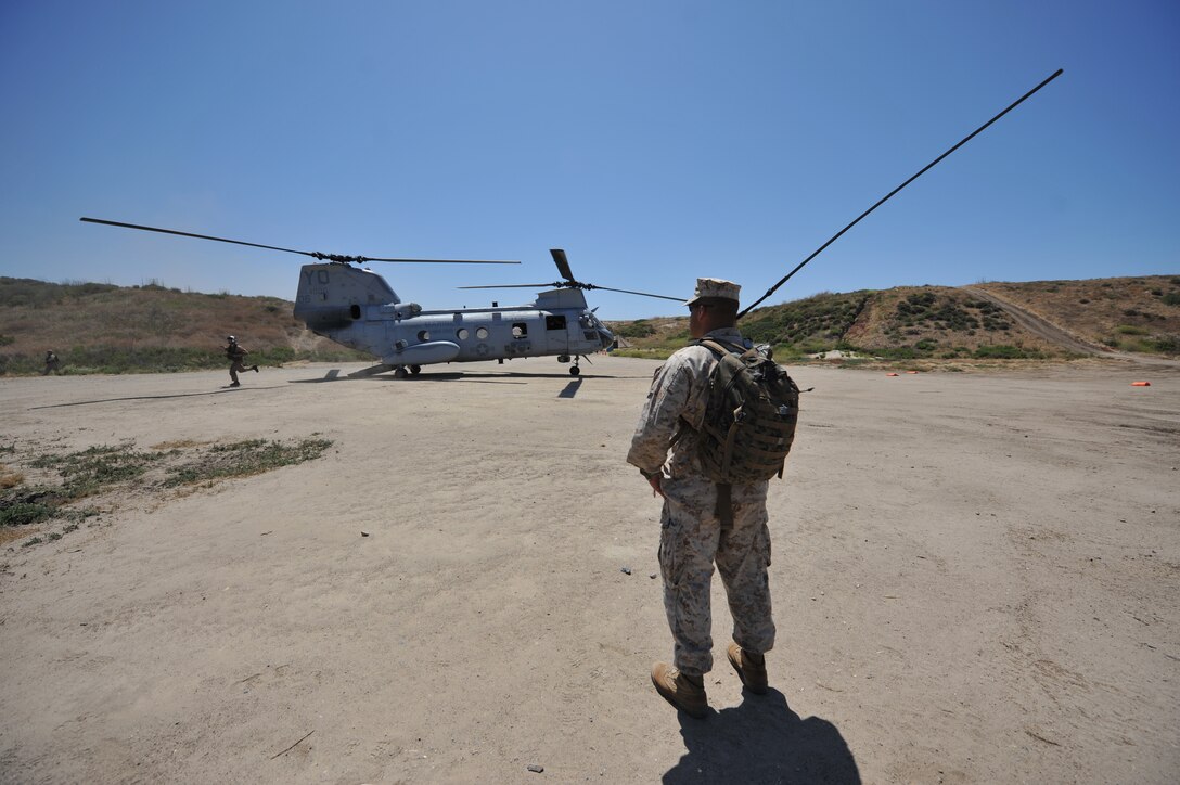 CAMP PENDLETON, Calif. -- Staff Sgt. Nathan M. Legassey, a Worchester, Mass., native and scout observer serving with the 11th Marine Expeditionary Unit's command element, clears a landing zone for a CH-46E Sea Knight helicopter that delivered simulated casualties to a medical team at Red Beach here June 18. The Marines are practicing casualty evacuations in preparation for a deployment later this year.